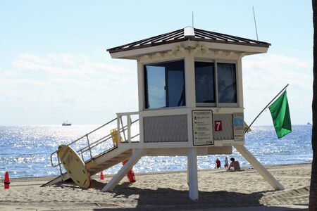 FORT LAUDERDALE, FLORIDA - FEBRUARY 5, 2013  Coastal beach lifeguard station tower 7 flying a green low hazard flag views signs, surfboards, people, boats and surfboard along sunny Atlantic ocean のeditorial素材