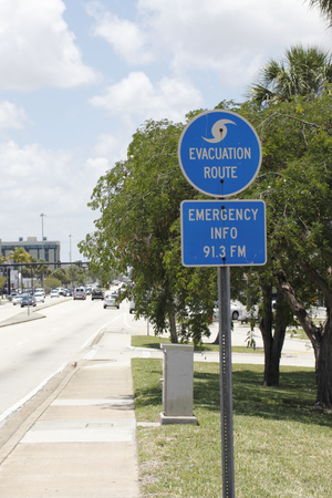 FORT-LAUDERDALE, FL, USA - JUNE 5, 2014: Blue and white evacuation route and emergency info 91.3FM signs with a symbol of a wave on top posted along Oakland Park Boulevard on a sunny day.のeditorial素材