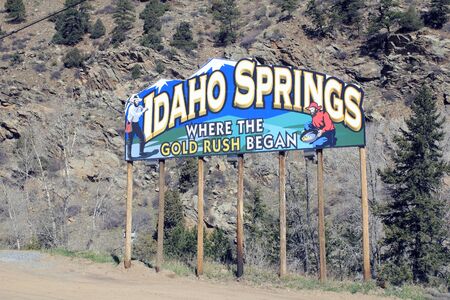 Idaho Springs, CO, USA - April 23, 2014: Large and colorful entry sign on the side of Interstate 70 near town saying, Idaho Springs Where the Gold Rush Began. In the sign a man stands with a mining pick and another man pans for gold.のeditorial素材