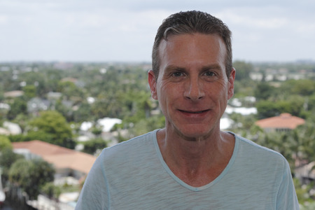 Good looking caucasian male in is forties with a nice smile outside on a tenth floor balcony showing a high view of residential and commercial areas of Fort Lauderdale, Florida on a sunny day.の写真素材