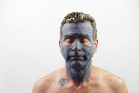 Male in his late forties wearing a charcoal and bentonite clay face mask beauty treatment. Front portrait of a white male wearing a bentonite mud mask beauty treatment.の写真素材
