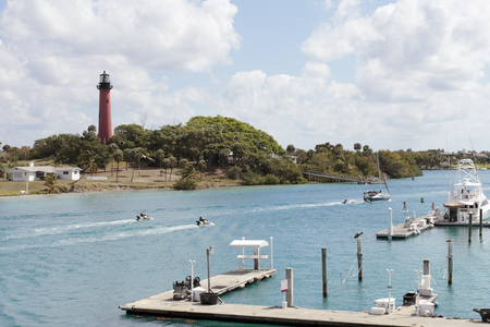 Jupiter, FL, USA - March 30, 2017: Boat docks and people on jet skis, boats and paddle boards in the Loxahatchee River. People on watercraft on Jupiter Inlet near a lighthouse.のeditorial素材