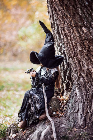 Beautiful girl witch. little girl in which costume celebrate Halloween outdoor and have a fun. Kids...