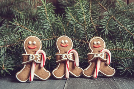 Gingerbread men with candy cane laying on grey wood background. Christmas or New Year composition....