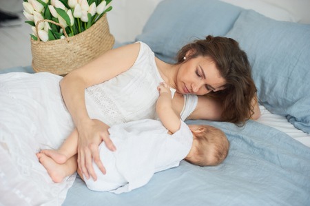 Ten month baby eating mother's milk. Mother breastfeeding baby. Young woman nursing and feeding...