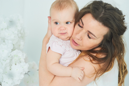 beautiful young mother with baby girl in her arms. The concept of a happy family, motherhood. mother playing with her baby in the bedroom. women's dayの写真素材