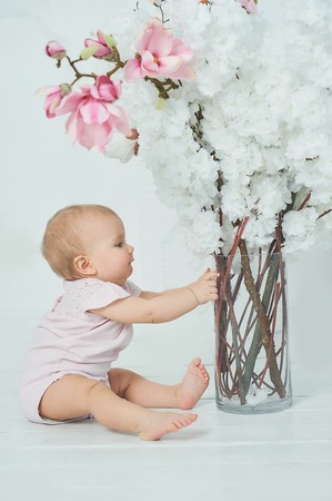 Adorable Ten month old toddler baby girl sitting on floor. Copy space. barefoot child sits on floor bootyの写真素材