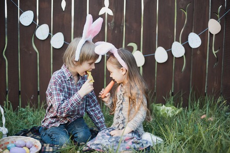 Little girl and boy eat a gingerbread cookie in the shape of the Easter egg. Easter celebration....