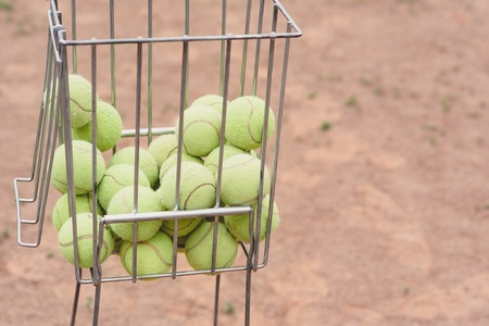 Tennis balls in the basket on the background of the tennis court. Old Tennis balls. copy spaceの写真素材