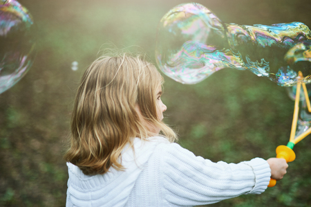 girl playing with giant soap bubble. Child blowing large bubblesの写真素材