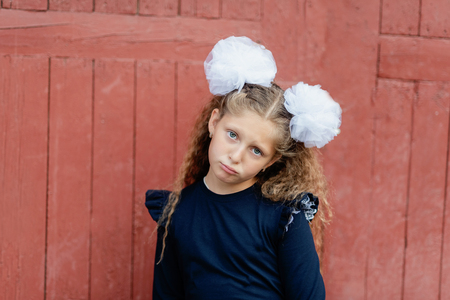 Portrait of a sad beautiful young schoolgirl is crying at the door of the school. does not want to go to school Farewell Bell. day of knowledge. beginning of the school year.の写真素材