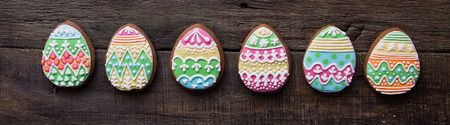 gingerbread cookie in the form of color eggs on dark wooden background. Happy Easter card. Bright biscuits. Treats for children. copy spaceの写真素材