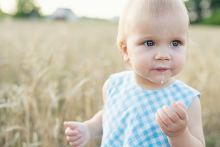 Little girl in wheat field. healthy child on picnic with bread and milk in golden cereal fieldの写真素材