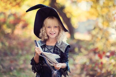 Beautiful girl witch. little girl in witch costume celebrate Halloween outdoor and have fun. Kids trick or treatingの写真素材