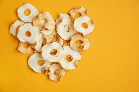 Slices of Dried apples on orange backround. fruit snack or ingredient for baking, cooking. Homemade...