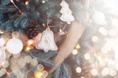 Closeup of Rustic Decorated Christmas tree on blurred, sparkling and fairy light background. Happy Holidays. Happy New Year and Xmas greeting card. Copyspace, selective focus. Eco wooden decorationsの写真素材