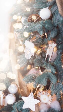 Closeup of Decorated Christmas tree on blurred, sparkling and fairy light background. Happy Holidays. Happy New Year and Xmas greeting card. Copyspace, selective focus. Eco wooden decorations. 9x16の写真素材