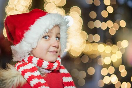 Child on christmas market. cute lovely girl in red hat standing at street happy about gingerbread cookies. Traditional leisure for families on xmas holidays. Family, tradition, holiday conceptの写真素材