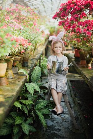 Cute funny girl with Easter bunny ears at garden. easter concept. Laughing child at Easter egg huntの写真素材