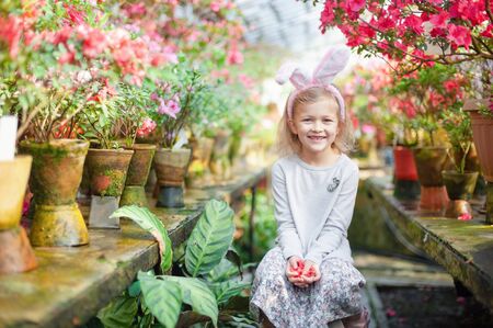 Cute funny girl with Easter bunny ears at garden. easter concept. Laughing child at Easter egg huntの写真素材