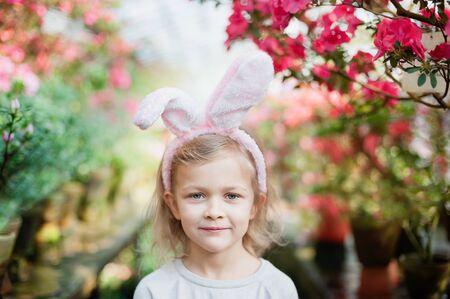 Cute funny girl with Easter bunny ears at garden. easter concept. Laughing child at Easter egg hunt
