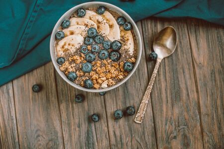 Healthy breakfast berry smoothie bowl topped with banana, granola, Blueberries and chia seeds with copy space. delicious blueberry smoothie bowl. vegan raw food. Selective focus. Flatlayの写真素材