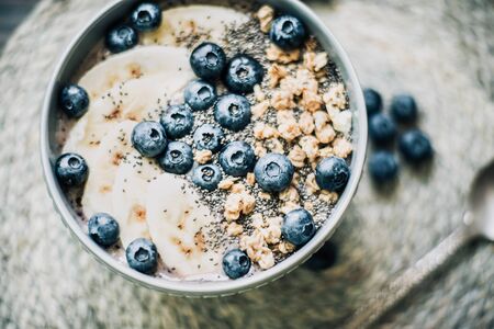 Healthy breakfast berry smoothie bowl topped with banana, granola, Blueberries and chia seeds with...