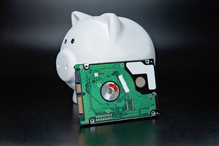 hard disk in piggy bank on black dark background. Business, backup March 31st and technology...
