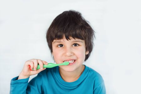 Little boy brushing his teeth on white background. little child cleans his teeth with toothbrush....