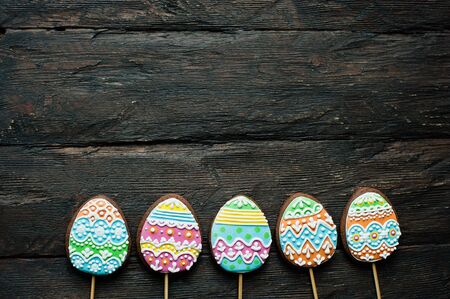 gingerbread cookie in the form of color eggs on dark wooden background. Happy Easter card. Bright...