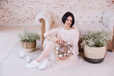 Easter wreath in hands of girl from natural vines with handmade decor. Wreath with flowers and eggs. Preparation and celebration of Happy Easter holidayの写真素材