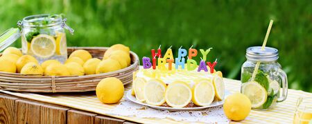 Birthday cake with happy birthday candles. Lemonade birthday party at summer park. food, celebration and festive concept. Mason jar glass of lemonade with lemons and straw.の写真素材