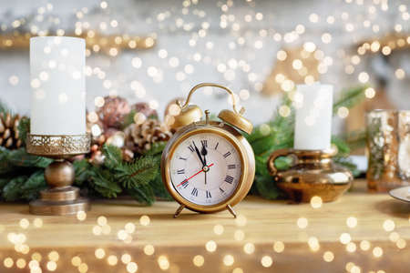 Vintage alarm clock in christmas kichen room showing five to midnight. Happy New Year starry background with bokeh Christmas lights.の写真素材