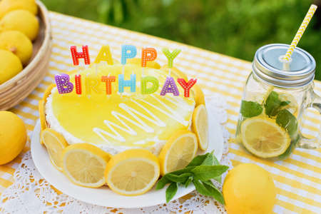 Birthday cake with happy birthday candles. Lemonade birthday party at summer park. food, celebration and festive concept. Mason jar glass of lemonade with lemons and straw.の写真素材