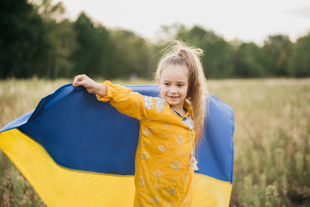 Girl carries fluttering blue and yellow flag of Ukraine in field. Ukraine's Independence Flag Day. Constitution day. 24 August. Patriotic holiday.の写真素材