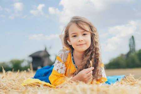 Ukraine's Independence Flag Day. Girl in traditional embroidery with flag of Ukraine in field. Constitution day. 24 August. Patriotic holiday.の写真素材
