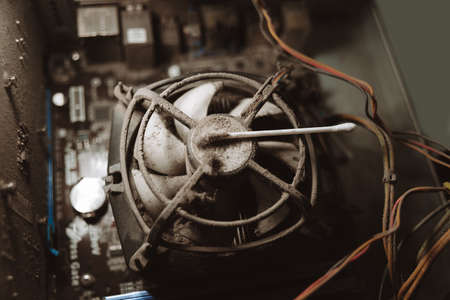 Dust on computer pc processor cooler with mainboard and computer case fragment. Selective focus. close up, macro. concept of cleaning parts of computerの写真素材