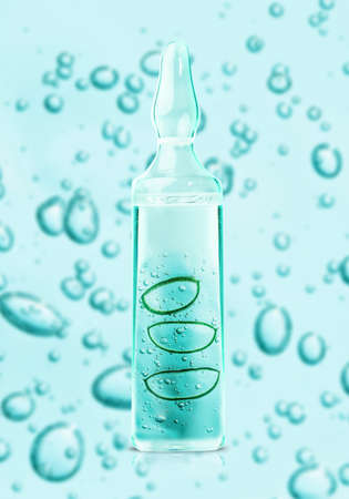 Aloe vera slices and gel cosmetic texture in glass bottle ampoule on blue bubbles background with...