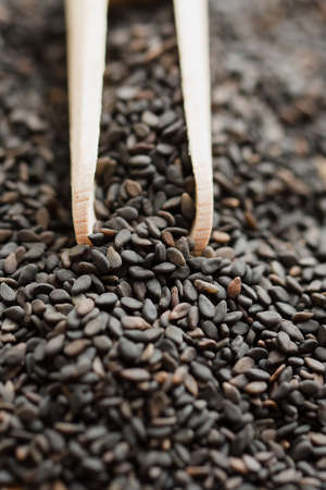 Close up of black sesame seed on wooden spoon background top view.