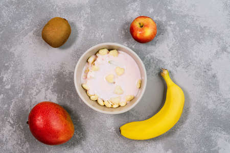 Healthy food granola in bowl. Fresh granola, muesli with kiwi, banana and nuts in gray bowl on background. Preparation for cooking at home, all mixed in bowl. Flat lay, from above, top view.の写真素材