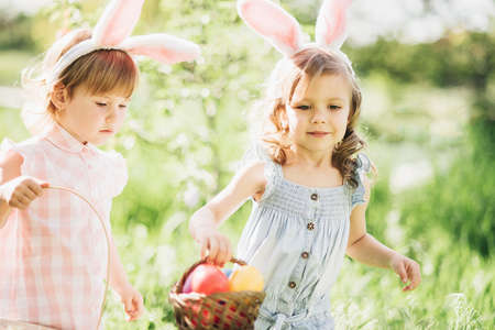 Easter egg hunt. Group Of Children Wearing Bunny Ears Running To Pick Up colorful Egg On Easter Egg Hunt In Garden. Easter traditionの写真素材