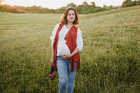 Outdoor Lifestyle portrait of pregnant woman expecting baby at sunset in nature. Expecting belly. Concept of pregnancy, maternity. Freedom concept. Enjoyment. Young woman relaxing enjoying fresh airの写真素材