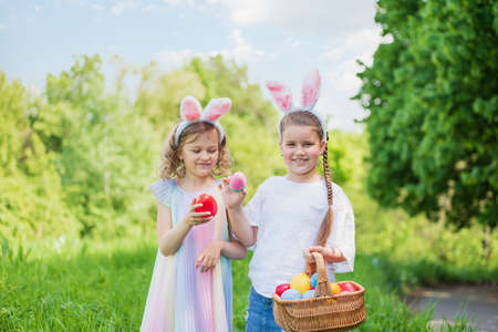 Easter egg hunt. Group Of Children Wearing Bunny Ears Running To Pick Up colorful Egg On Easter Egg Hunt In Garden. Easter tradition. Laughing children in park with basket spring conceptの写真素材
