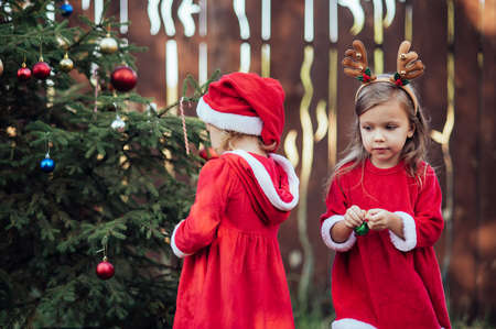 Christmas in july. Children waiting for Christmas in wood in july. portrait of little girls decorating christmas tree. winter holidays and people concept. Merry Christmas and Happy Holidays.の写真素材