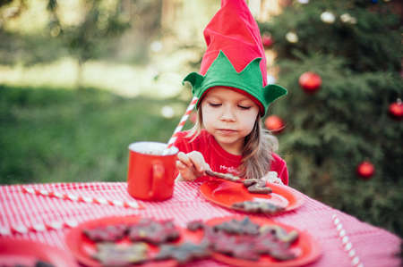 Christmas in july. Child waiting for Christmas in wood in july. portrait of little girl drinking hot cocoa with marshmallow and gingerBread man cookies. Merry Christmas and Happy Holidays.の写真素材