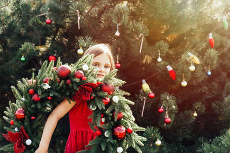 Merry Christmas. Portrait of happy funny child girls in Santa hat with Christmas wreath. Happy Holidays. Fairy Magic. Happy kid enjoying holiday. Christmas in Julyの写真素材