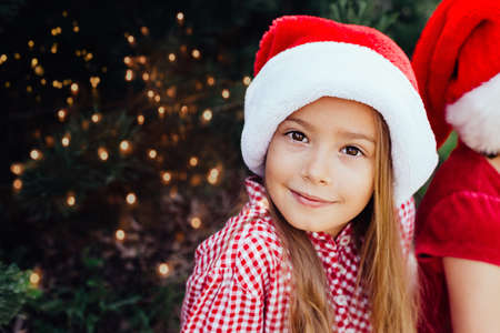 Merry Christmas. Portrait of funny child girl in Santa hat eating gingerbread cookies drinking hot...