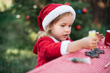 Christmas in july. Child waiting for Christmas in wood in july. portrait of little girl drinking hot cocoa with marshmallow and gingerBread man cookies. Merry Christmas and Happy Holidays.の写真素材
