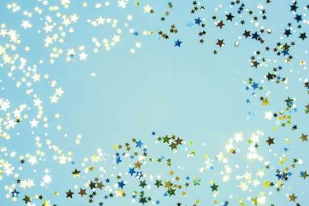 Holiday Festive background. gold and silver star confetti glitter scattered on blue background....