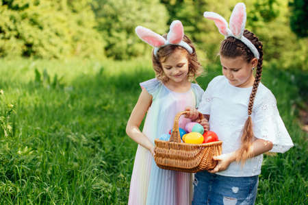 Easter egg hunt. Group Of Children Wearing Bunny Ears Running To Pick Up colorful Egg On Easter Egg...